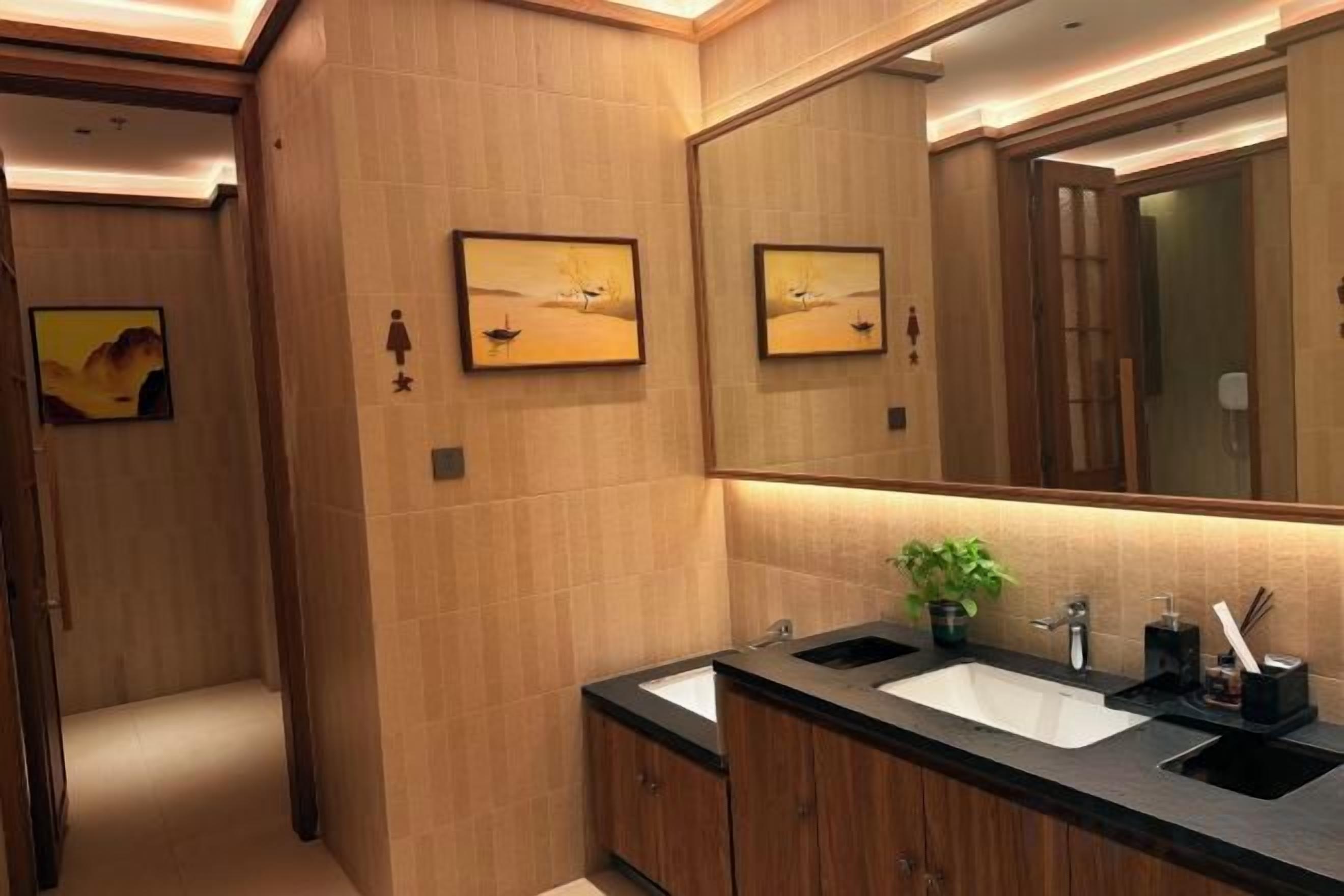 Un baño moderno con lavamanos doble, armarios de madera y un espejo grande.