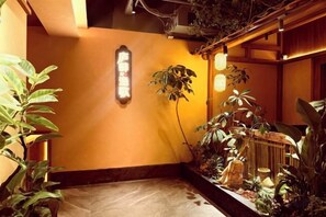 Um interior japonês tradicional com piso de tatame, um painel shoji e diversas plantas de interior.