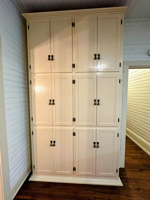 A large white wardrobe with multiple doors and handles, located in a room with wooden flooring and white walls. - Casa Tejas in Taylor TX (Taylor)