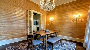 A dining area with a wooden wall, a chandelier, a table with chairs, and a patterned rug. - Casa Tejas in Taylor TX (Taylor)