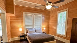 A bedroom with a wooden ceiling, a ceiling fan, a bed with a headboard, two bedside tables with lamps, and a window with blinds. - Casa Tejas in Taylor TX (Taylor)