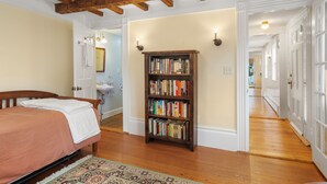 A bedroom with a bed, a bookshelf, and a hallway leading to a bathroom. - Entire 4BR 2 Bath Home l Minutes to Downtown Salem (Salem)
