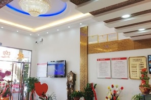 A reception area with a chandelier, a clock, and informational posters on the wall. - Tianzun Business Hotel (Liancheng)