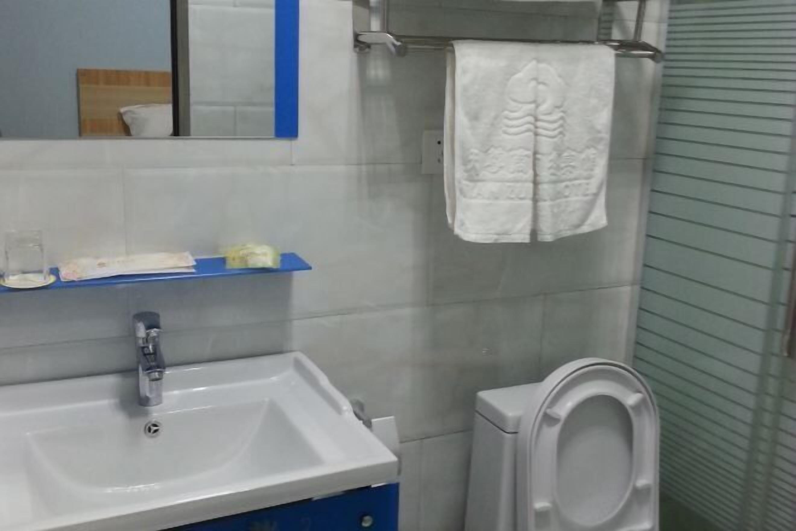A bathroom with a white sink, a mirror, a towel hanging on a rack, and a toilet.