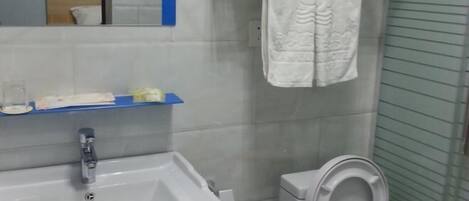 A bathroom with a white sink, a mirror, a towel hanging on a rack, and a toilet.
