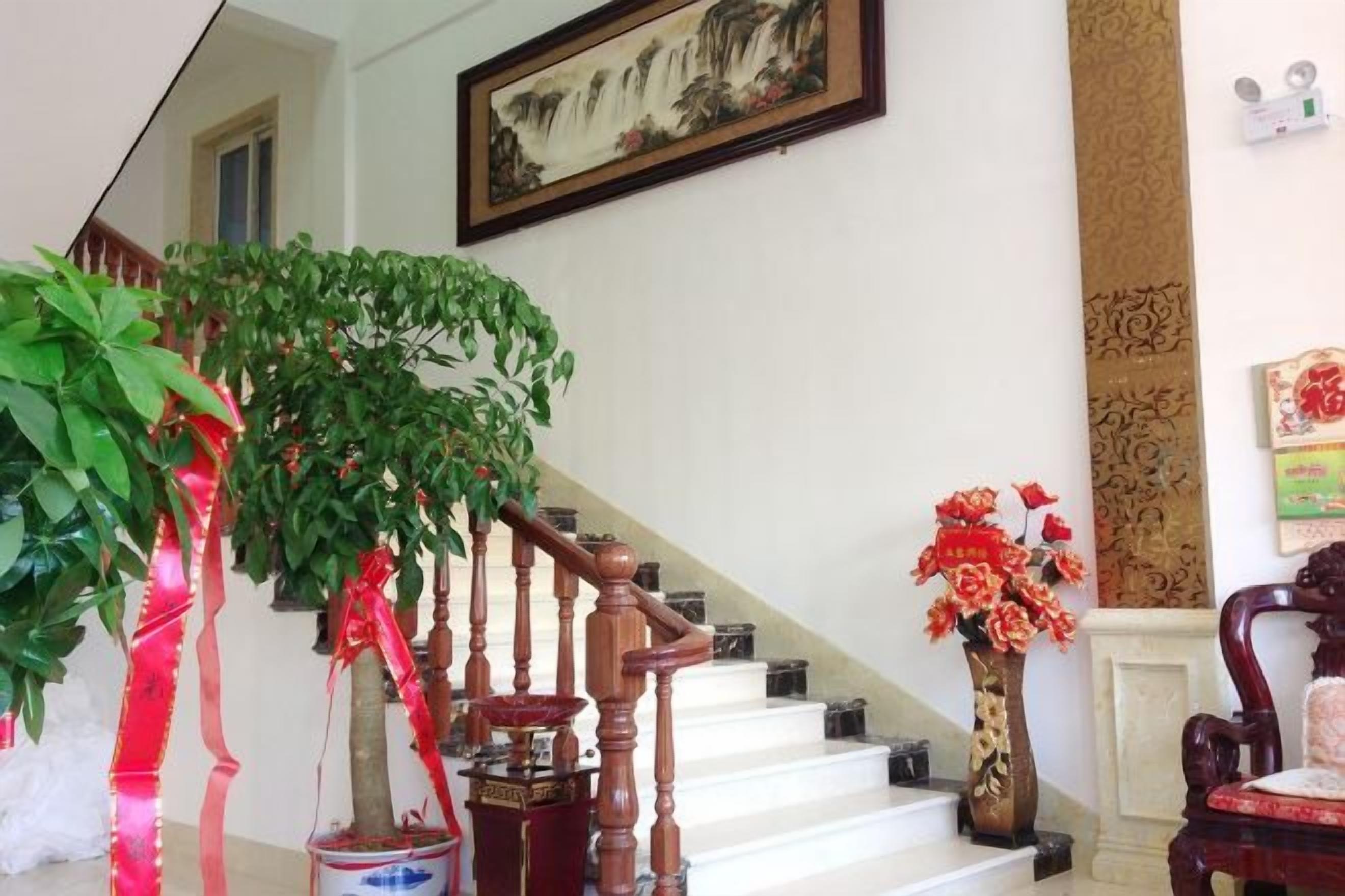 A staircase with a wooden handrail, a potted plant, and a vase with flowers.