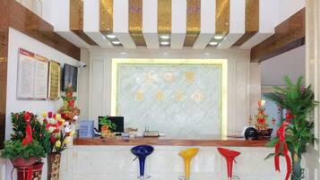 A reception area with a marble counter, a digital screen, and a decorative wall with gold accents.