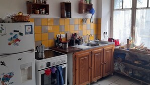Una cucina con frigorifero, piano cottura e forno, mobili in legno, una finestra con vista e diversi oggetti da cucina sugli scaffali.