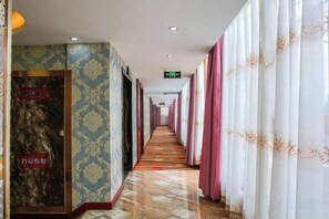 A hotel corridor with patterned walls, a tiled floor, and curtains on both sides. - Aifeng Hotel (Yiwu Gongren North Road) (Yiwu)