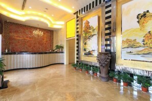 A hotel lobby with a reception desk, a large painting, and potted plants. - Aifeng Hotel (Yiwu Gongren North Road) (Yiwu)