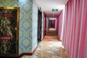 A hotel corridor with patterned walls, a tiled floor, and pink curtains. - Aifeng Hotel (Yiwu Gongren North Road) (Yiwu)
