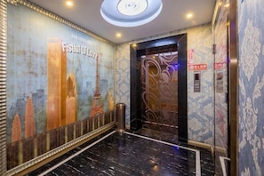 A hotel lobby with a marble floor, a mural of a cityscape, and an elevator. - Aifeng Hotel (Yiwu Gongren North Road) (Yiwu)