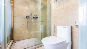 A modern bathroom with a glass shower enclosure, a white toilet, and a marble-tiled wall.