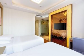 A hotel room with two beds, a TV, and a glass shower enclosure.