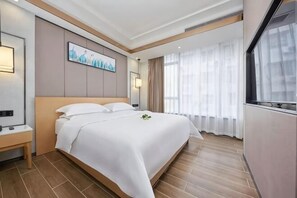 A hotel room with a large bed, a bedside table, a window with curtains, and a painting on the wall. - Aifeng Hotel (Yiwu Gongren North Road) (Yiwu)