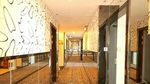 A hotel corridor with patterned carpet, glass doors, and a mirrored wall. - Aifeng Hotel (Yiwu Gongren North Road) (Yiwu)