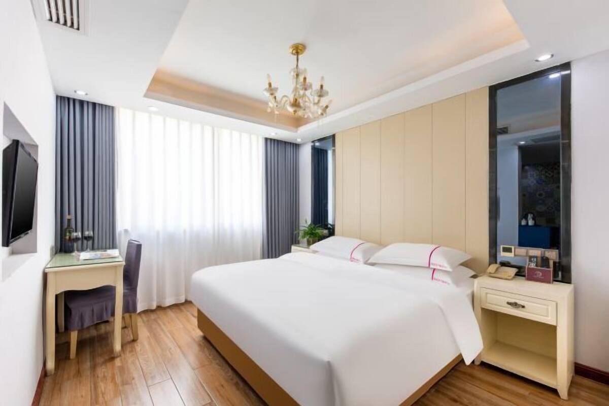 Une chambre d’hôtel avec un grand lit, un bureau avec une chaise, une télévision et une table de chevet avec une lampe.