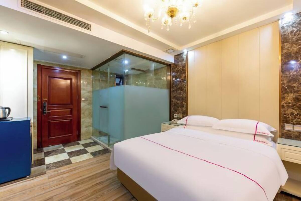 Une chambre d’hôtel avec un lit, un bureau, une douche et une porte.