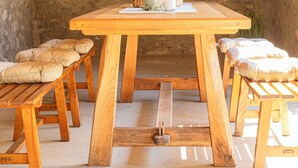 Ein rustikaler Raum mit Steinwänden, einem Holztisch und Bänken.