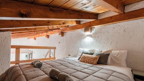 Ein Schlafzimmer mit Holzboden, einem Bett mit einer beige farbenen Tagesdecke und einem Nachttisch mit einer Lampe.