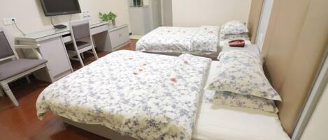 Une chambre d’hôtel avec deux lits, un bureau, une chaise et un téléviseur.