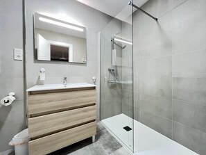 Bathroom features a vanity with a drawer unit, a large mirror, and a glass shower enclosure.
