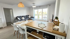 A modern kitchen with a wooden countertop, white chairs, and a dining table.