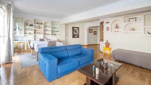 A spacious living room with a blue sofa, a coffee table, and a grey sofa. There is a dining area with a table and chairs in the background. - PUSHE Granada Plaza Menorca Art & Tradition (Granada)