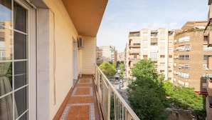 A balcony with tiled flooring, a metal railing, and a view of adjacent buildings. - PUSHE Granada Plaza Menorca Art & Tradition (Granada)