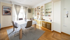 A dining area with a table set for four, a kitchen area with glass cabinets, and a framed picture on the wall. - PUSHE Granada Plaza Menorca Art & Tradition (Granada)