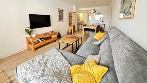 Una sala de estar moderna con un sofá gris, una mesa de centro de madera y un televisor de pantalla plana.