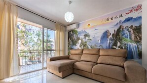 A modern living room with a beige sectional sofa, a large window with curtains, and a mural of a waterfall on the wall. - Casa de Sol (Fuengirola) (Fuengirola)