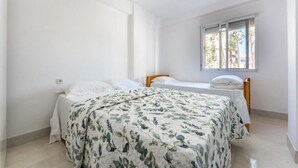 A bedroom with two beds, a window with blinds, and a tiled floor. - Casa de Sol (Fuengirola) (Fuengirola)