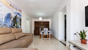 A modern living room with a sofa, a dining table with chairs, and a TV on a stand. - Casa de Sol (Fuengirola) (Fuengirola)