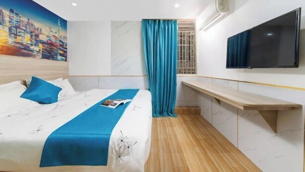 Une chambre d’hôtel avec un lit, une télévision, un bureau et un tableau représentant un paysage urbain accroché au mur.
