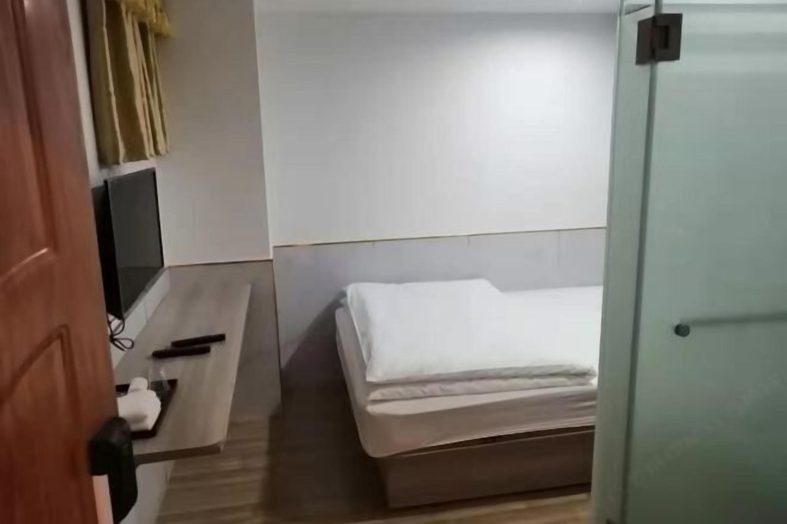 A small, modern room with a bed, a desk, and a chair.