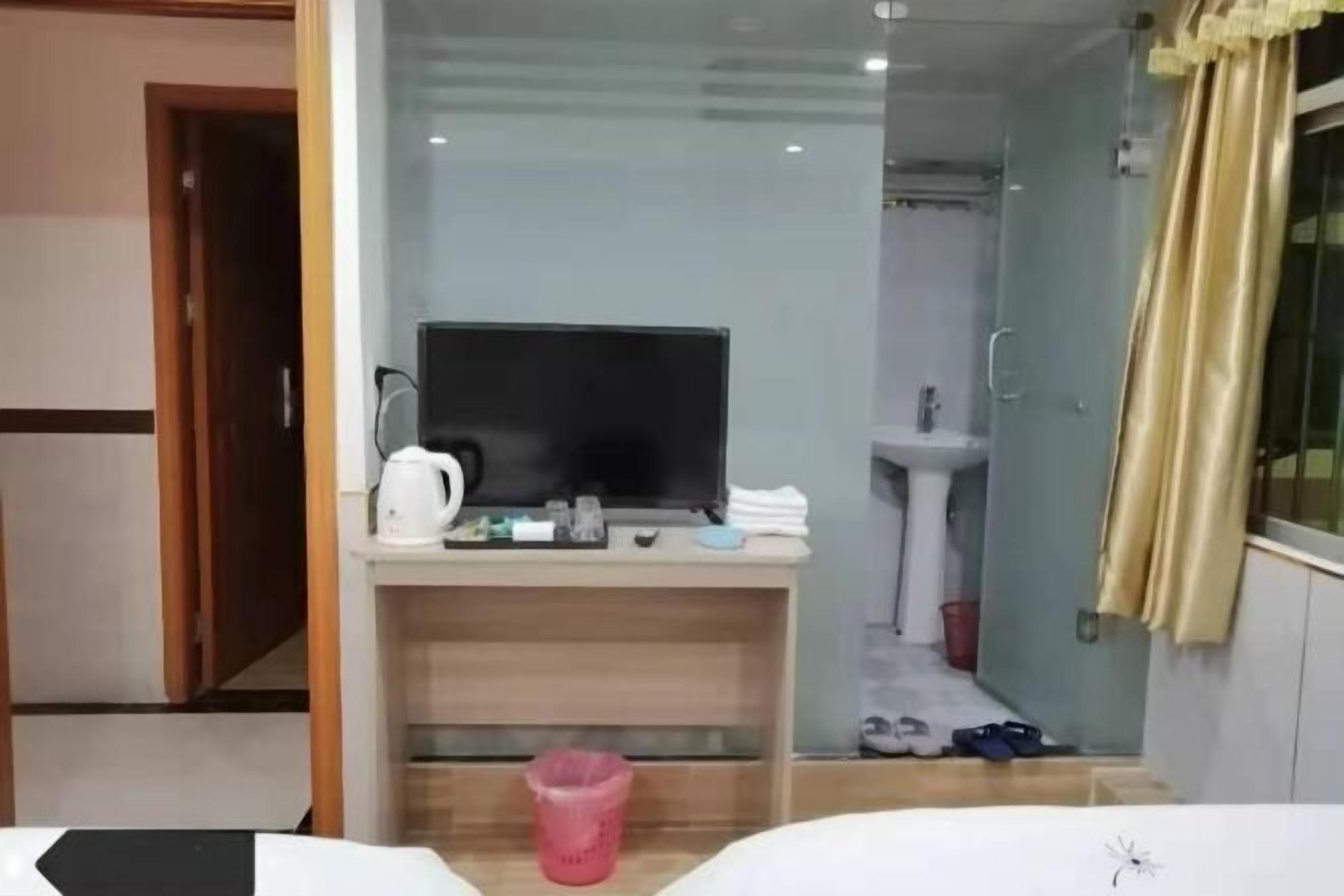 A hotel room with a desk, television, and a shower area.