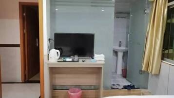 A hotel room with a desk, television, and a shower area.