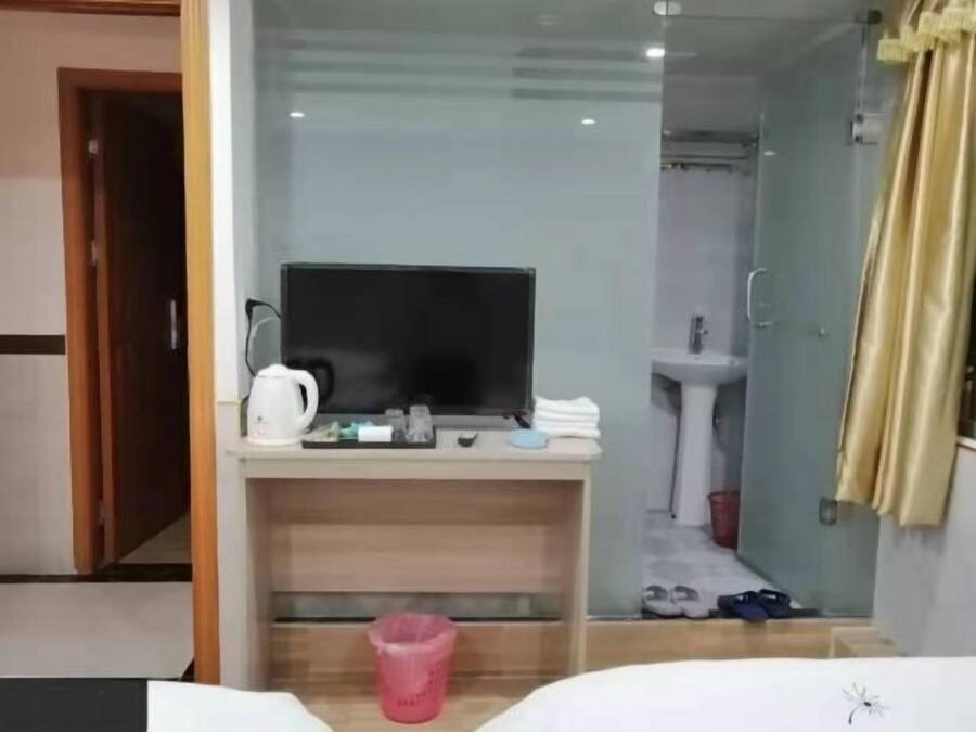 A hotel room with a desk, television, and a shower area.