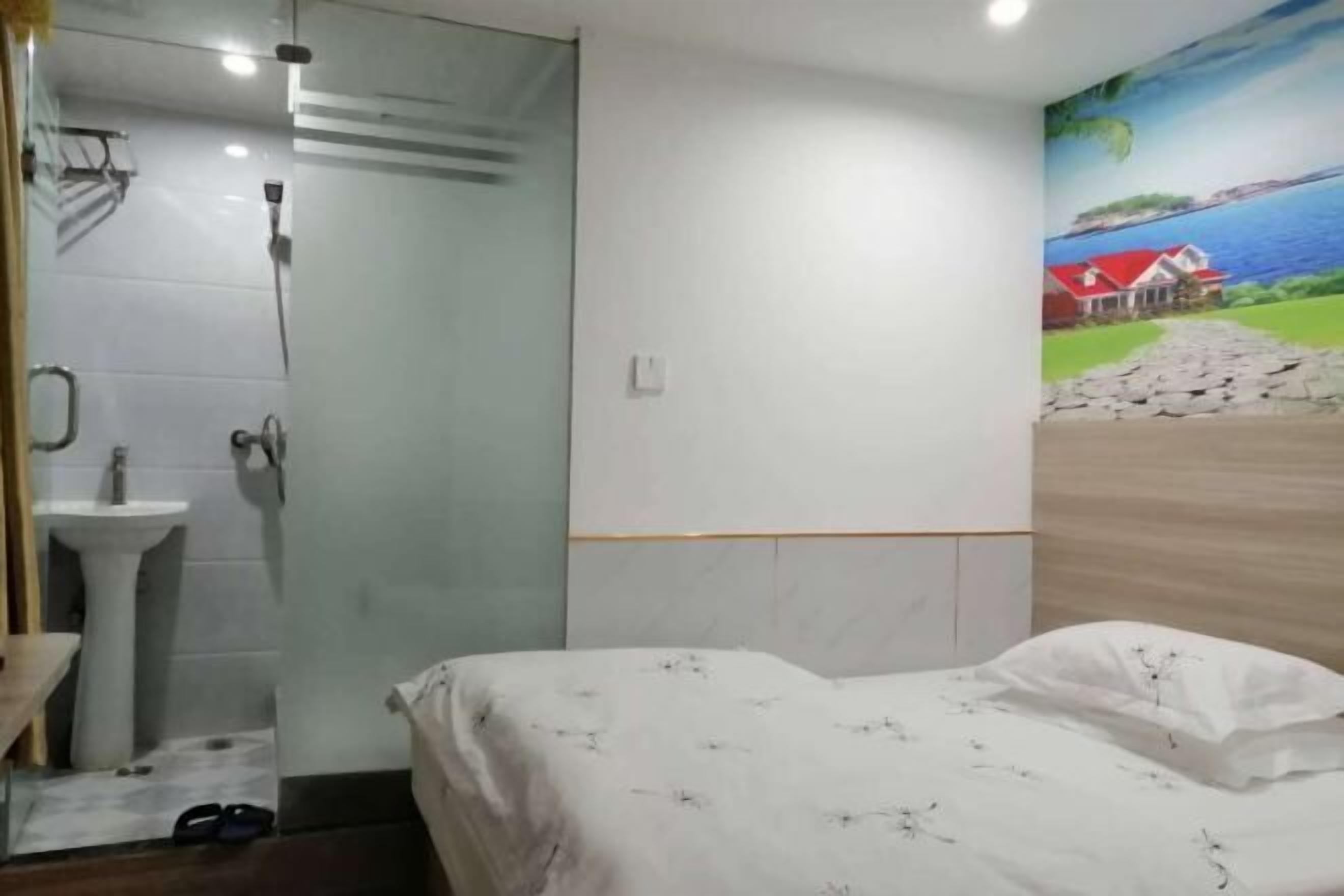 A bedroom with a bed, a shower, a sink, and a mural on the wall.