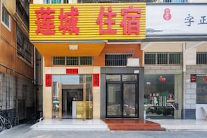 A hotel with a yellow signboard, a glass entrance, and a visible reception desk.
