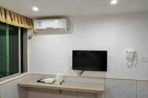 A hotel room with a mounted air conditioner, a flat-screen TV, a towel rack, and a small table with a kettle. - LianChen Hotel（Shenzhen North Railway Station） (Shenzhen)