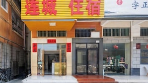 L’entrée d’un hôtel, reconnaissable à son panneau jaune bien visible, à ses portes en verre et à son espace d’entrée dégagé.