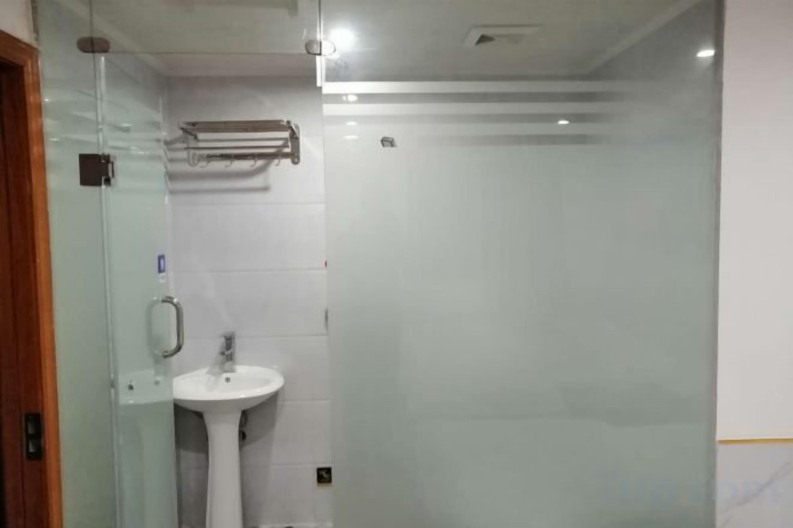 Ein Badezimmer mit einer Duschkabine aus Glas, einem Standwaschbecken und einem Handtuchhalter.