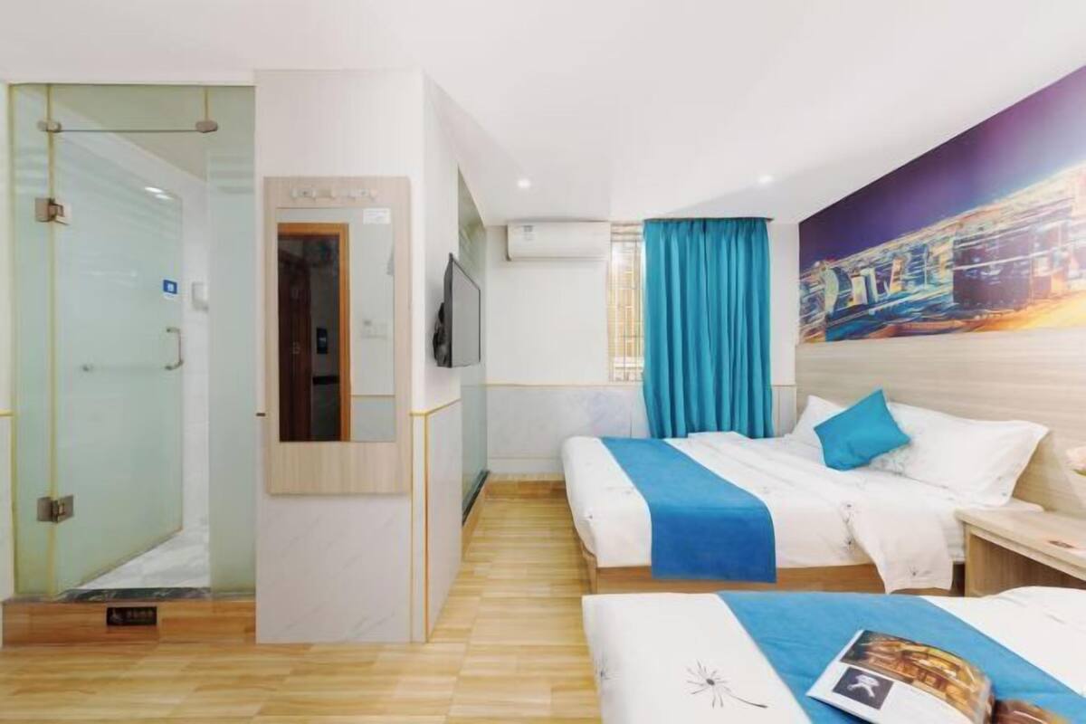 A hotel room with two beds, a TV, a painting, and a wooden floor.