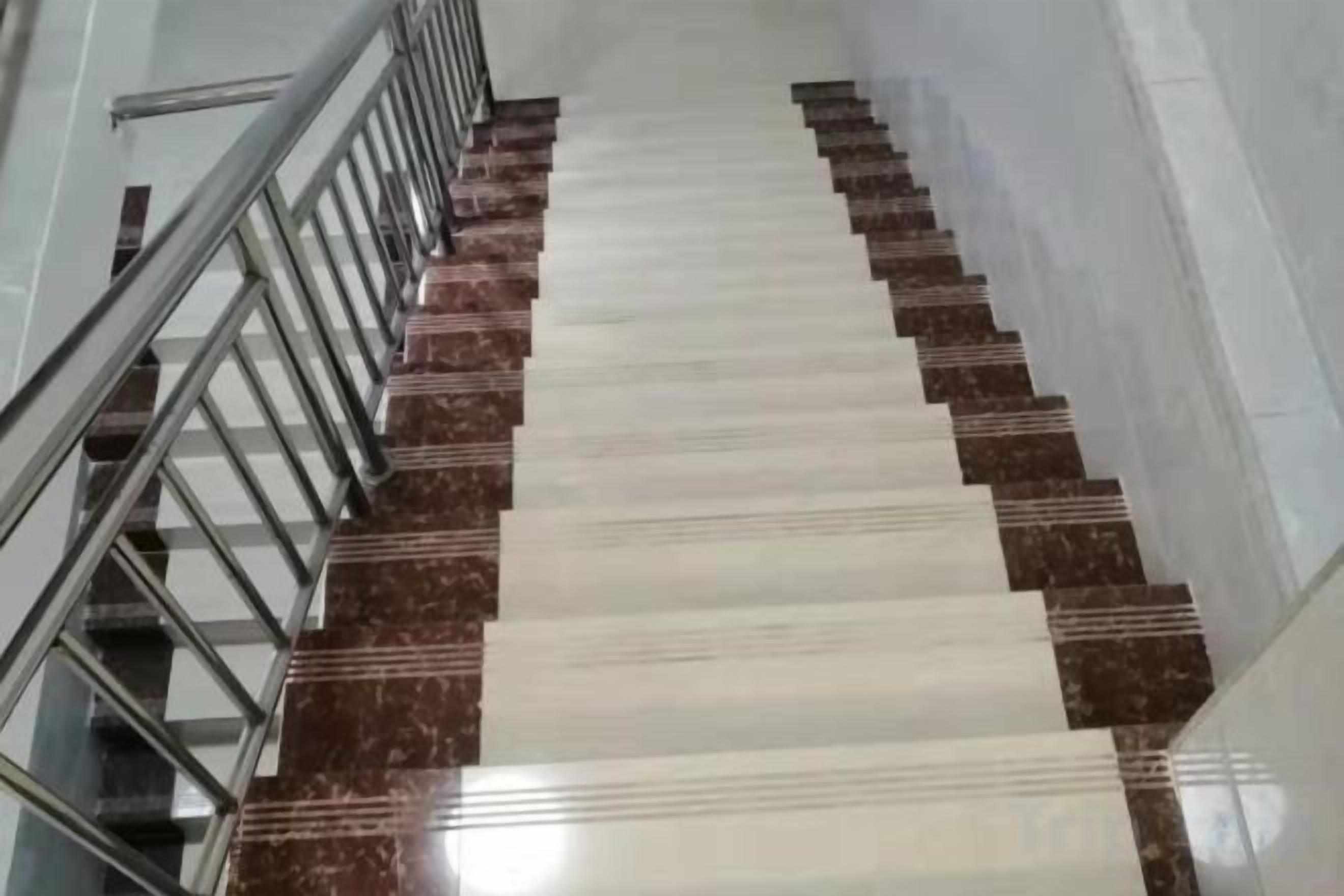 A staircase with alternating white and brown steps, metal handrails, and a straight, narrow pathway.