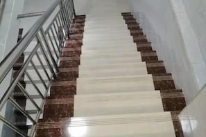 A staircase with alternating white and brown steps, metal handrails, and a straight, narrow pathway. - LianChen Hotel（Shenzhen North Railway Station） (Shenzhen)