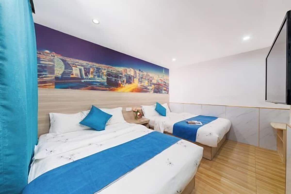 A hotel room with two beds, a cityscape mural, a flat-screen TV, and a wooden floor.