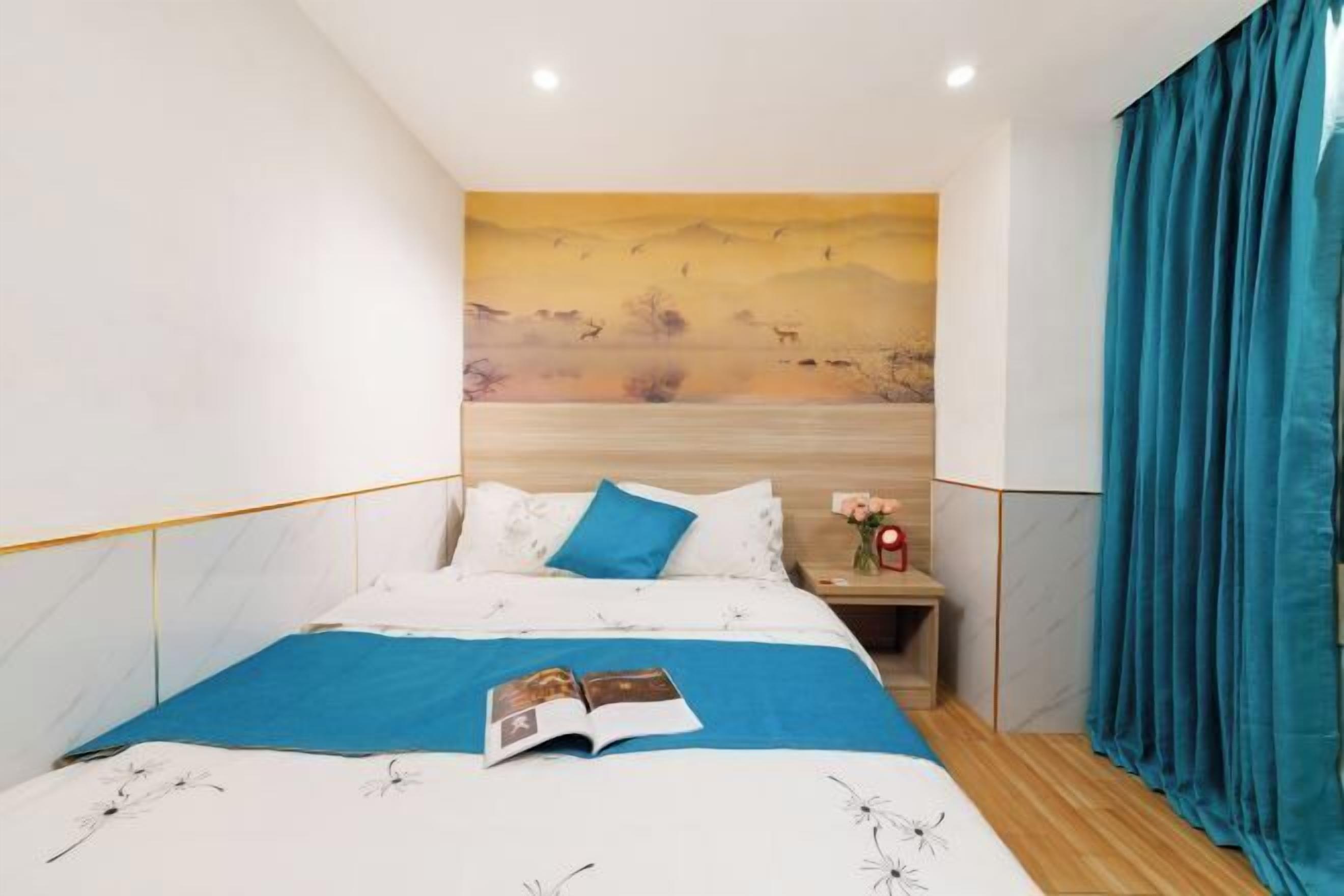 A bedroom with a bed, a nightstand, a wall art, and a window with curtains.
