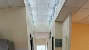 A corridor with tiled flooring, a ceiling with skylights, and a refrigerator on the left. - Villa Lorena Casa de Huespedes (San Salvador)